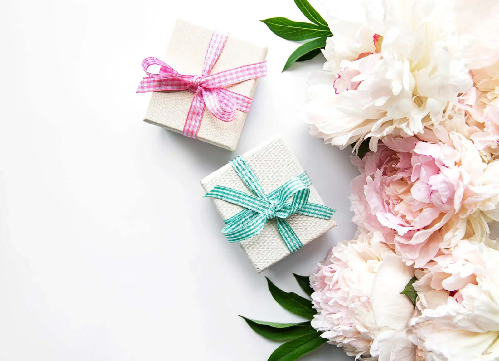 Seasonal Flower Bouquet with pink and white peonies next to wrapped gifts on white background