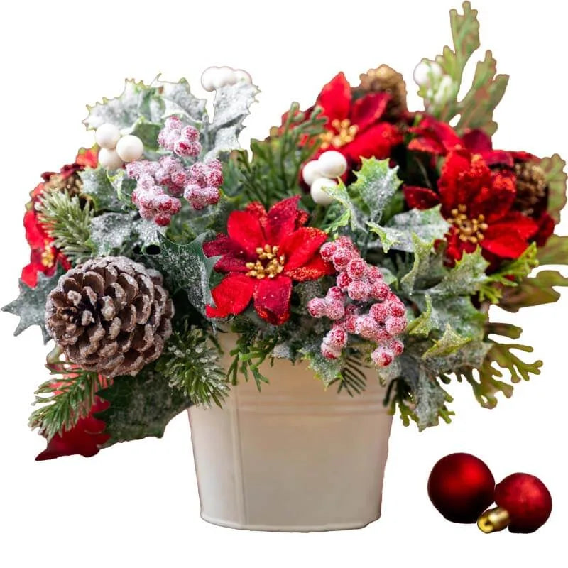 Festliches Weihnachts-Arrangement mit roten Blüten, Tannenzapfen und Beeren in einem weißen Topf