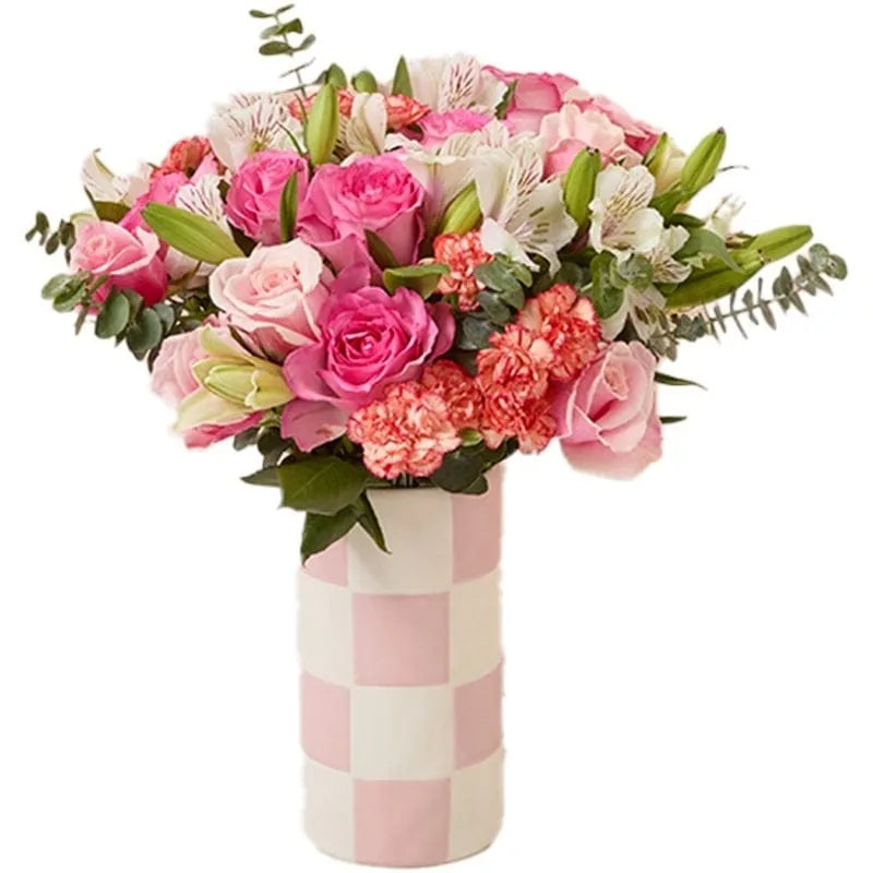 Verschiedene rosa Blumen in einer karierten Vase arrangiert.