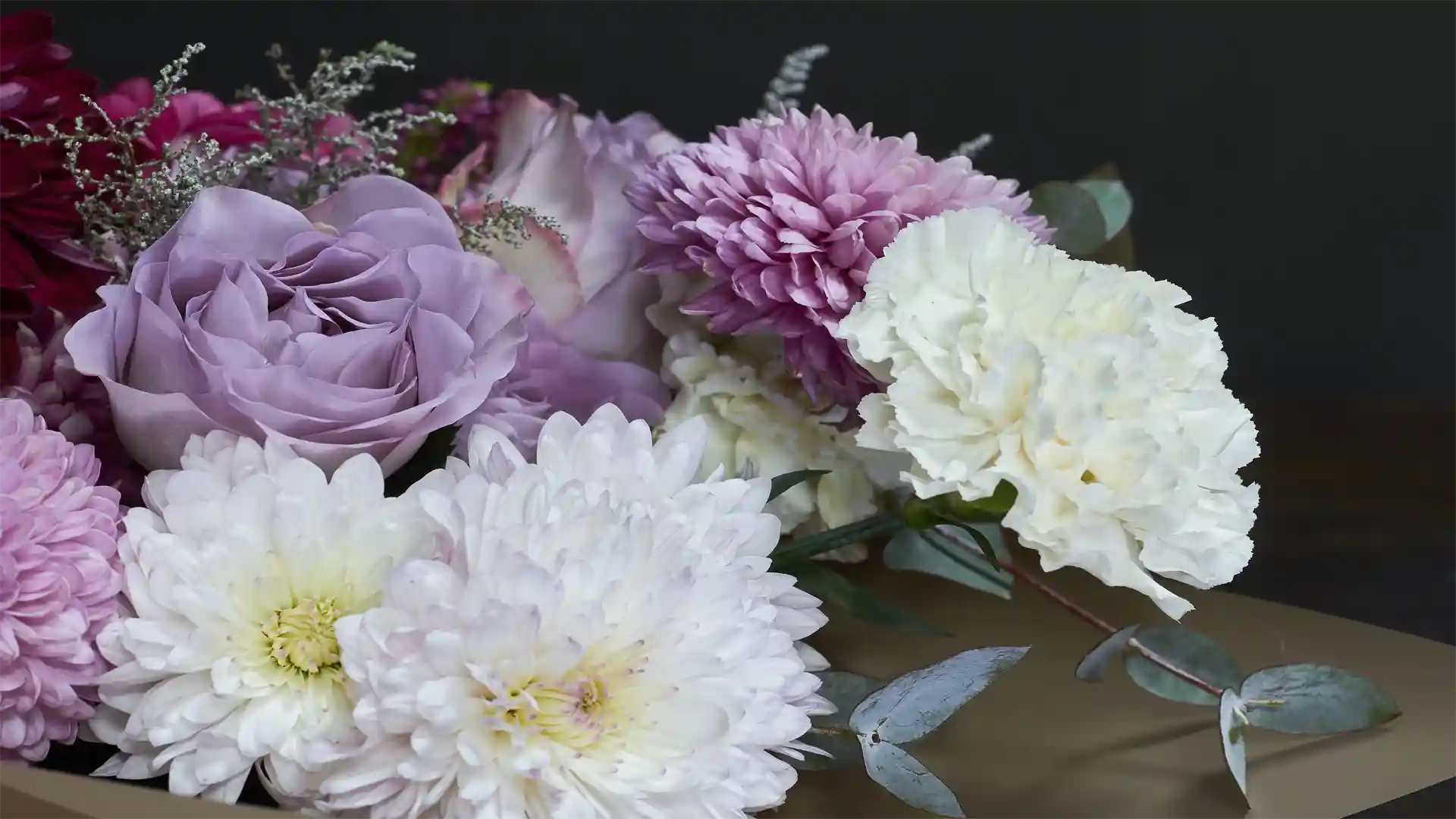 Bouquet of flowers with purple, white, and pink colors on a dark background