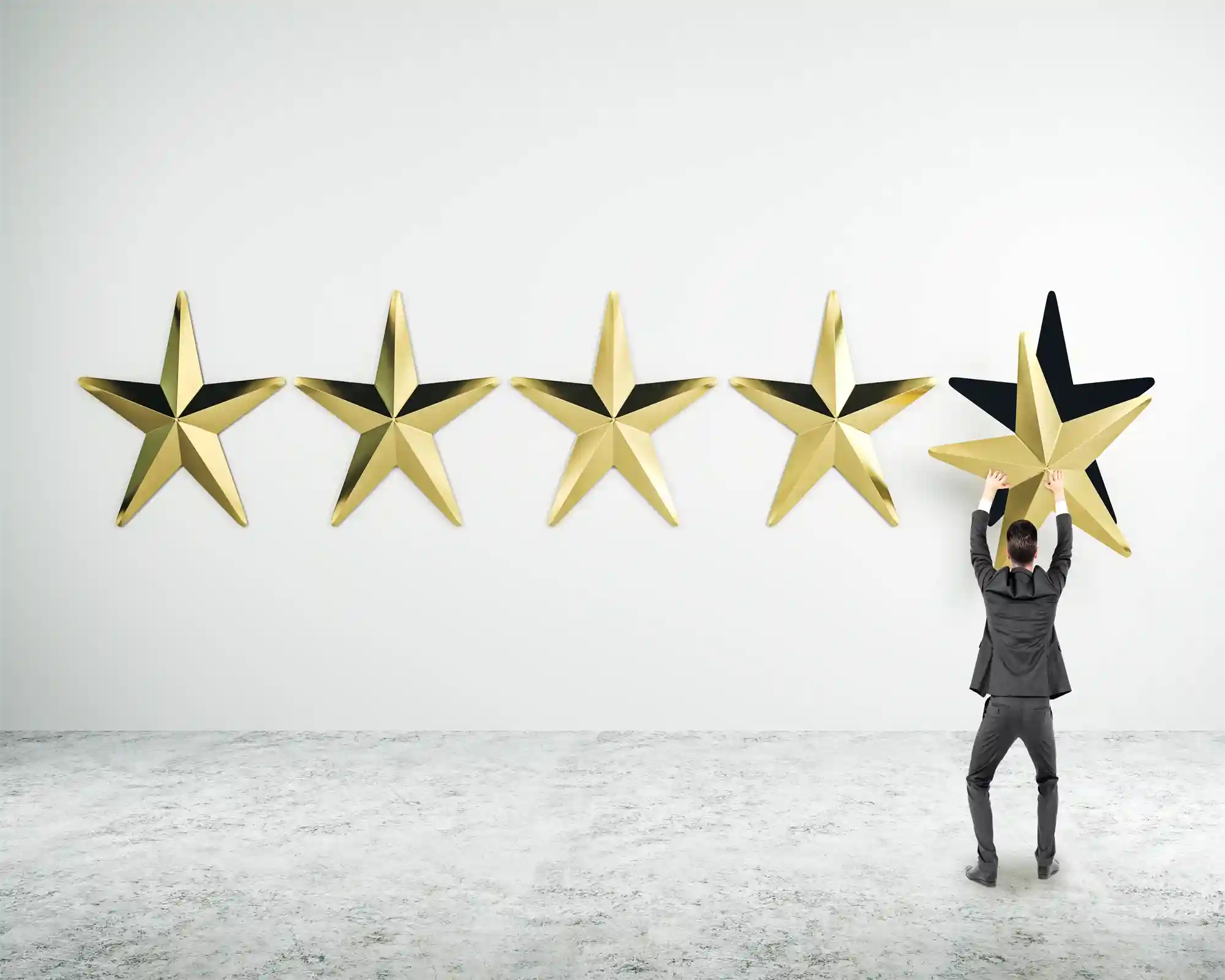 Man holding a large gold star against a white background with five other stars displayed.