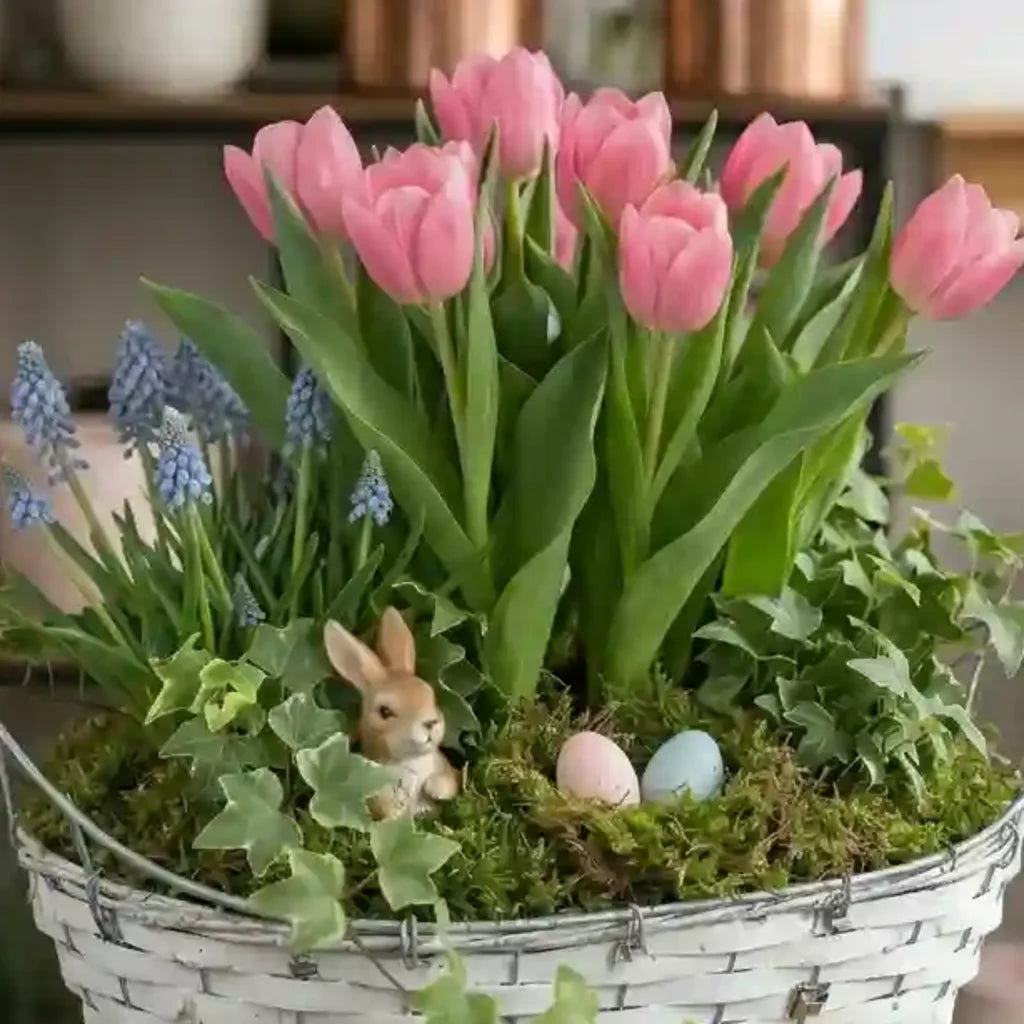 Modernes Frühlingsgefäß mit rosa Tulpen und blauen Traubenhyazinthen von MO BLUMEN in einem weißen Korb mit Moos, Eiern und Häschen-Dekoration.