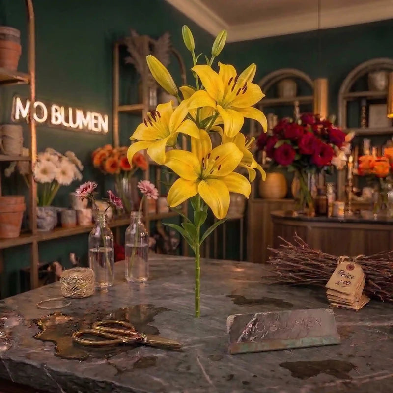 Gelber Lilienzweig mit leuchtenden gelben Blüten und Knospen von MO BLUMEN auf dunkler Theke mit Wassertropfen und Schere.