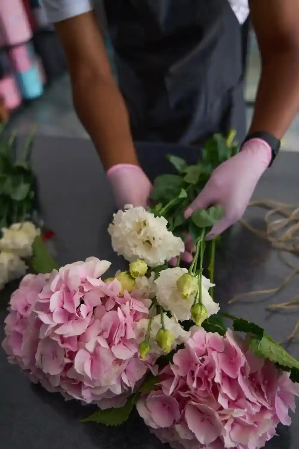 Person arranging flowers with pink gloves on a table