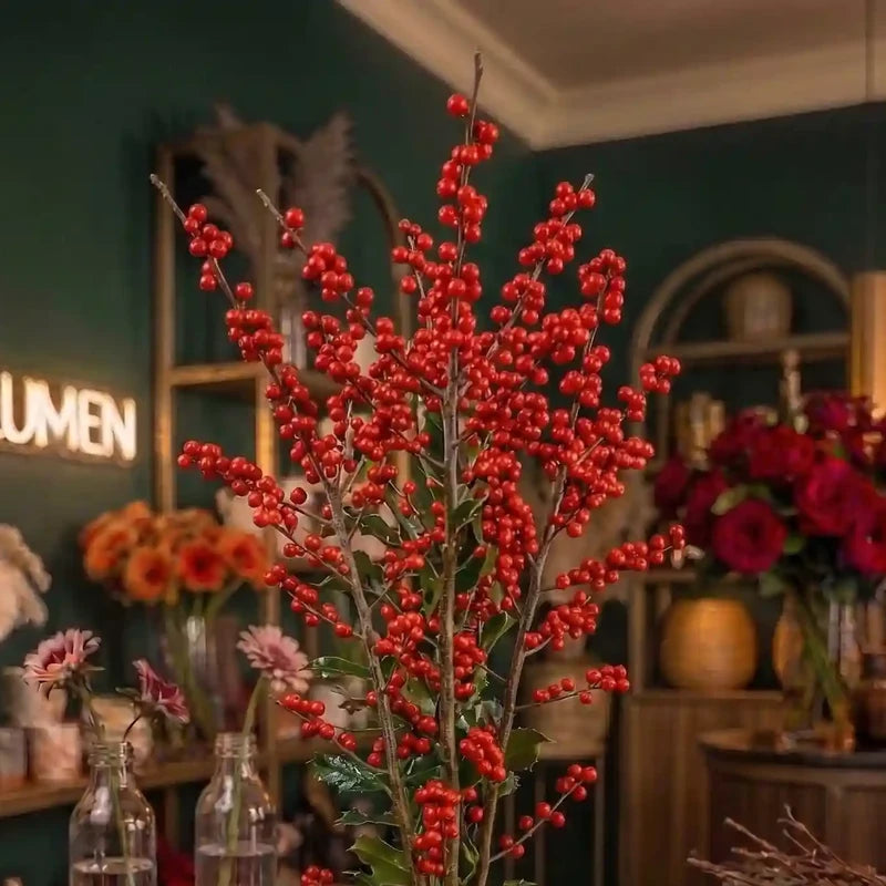 Ilex-Zweige mit leuchtend roten Beeren von MO BLUMEN, aufrecht in einer Vase arrangiert.