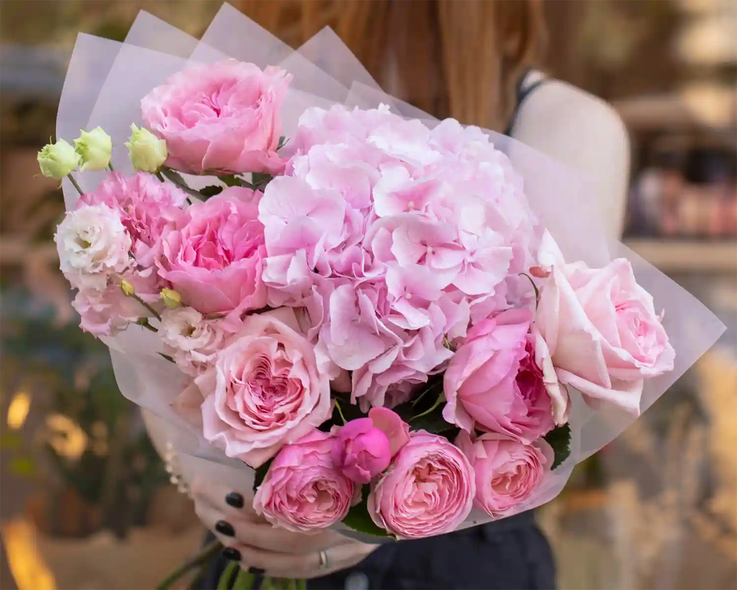 Bouquet of pink flowers held by a person with a blurred background