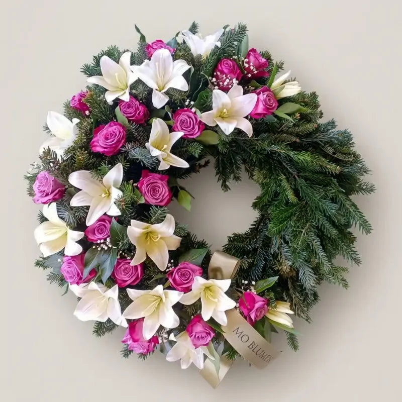 Trauerkranz mit weißen Lilien und rosa Rosen von MO BLUMEN, aus Tannengrün mit goldenem Band.