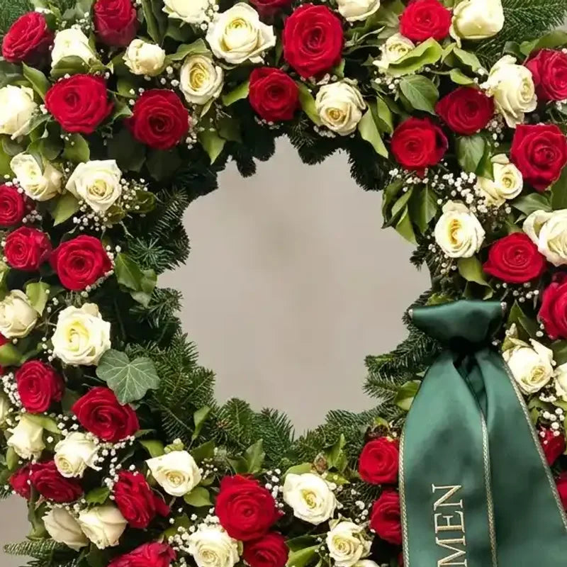 Luxuriöser Trauerkranz mit roten und weißen Rosen von MO BLUMEN, aus Tannengrün, kleinen weißen Blüten und einem grünen Band mit der Aufschrift "MEN".