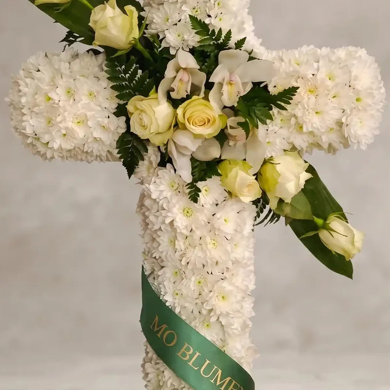 Weißes Trauerkreuz mit Orchideen von MO BLUMEN, dekoriert mit hellgelben Rosen und einem grünen Band.